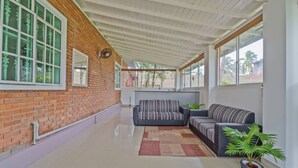 A spacious living area with a brick wall, large windows, and two sofas. - Amy's Haven (Wadduwa)