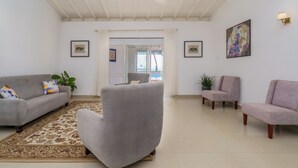 A spacious living room with a grey sofa, a grey armchair, and a small table. There are two framed pictures on the wall and a potted plant. - Amy's Haven (Wadduwa)