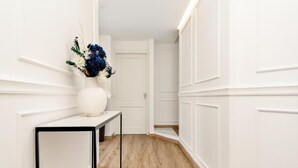 Un pasillo con paredes blancas, suelo de madera y una puerta blanca al final.