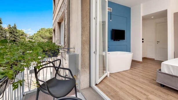 Un apartamento moderno con balcón, un ventanal grande y una bañera empotrada.