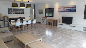 Uma sala de estar moderna com área de jantar, sofá, televisão e obras de arte nas paredes.