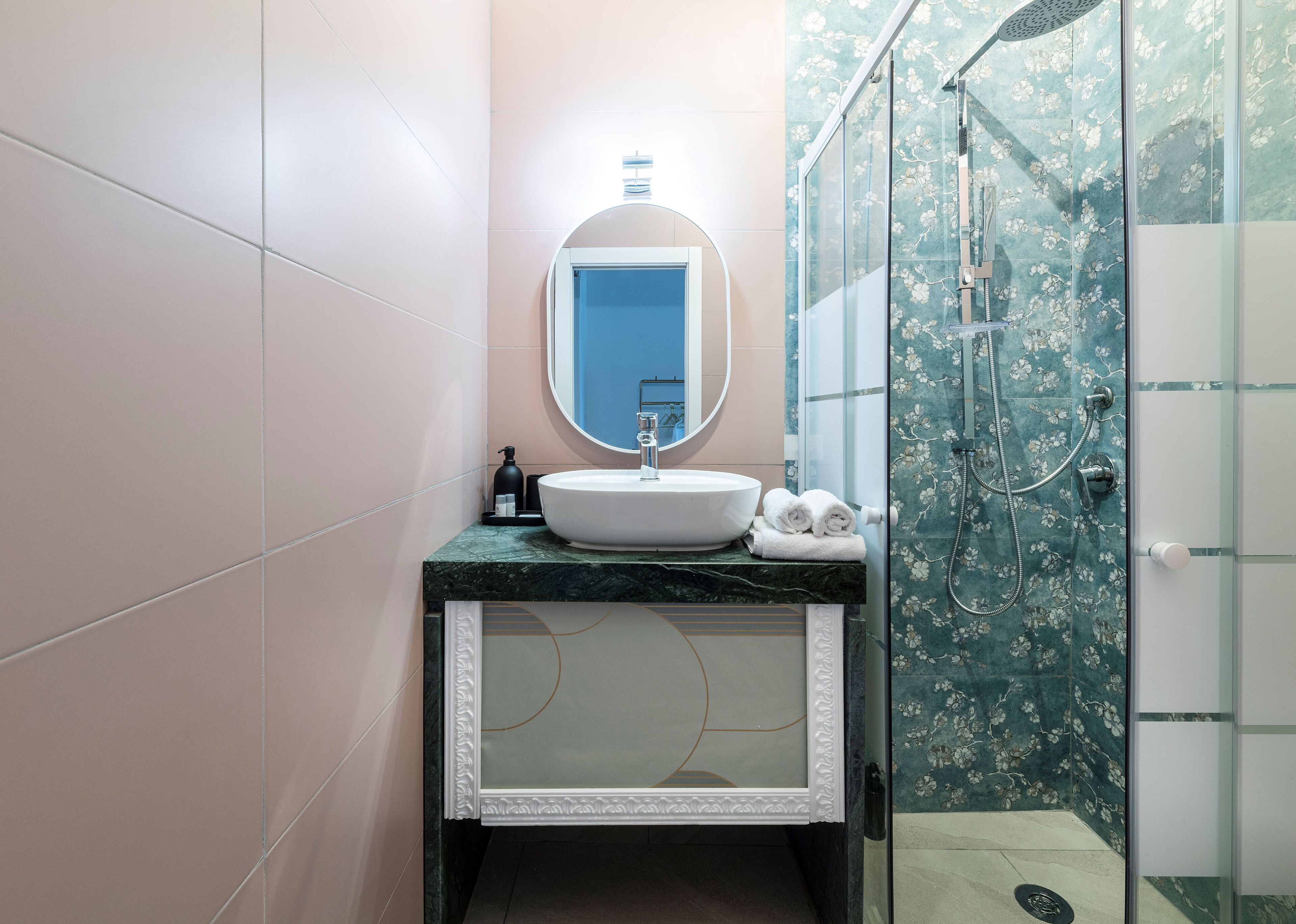 A bathroom with a round mirror, sink, and shower.