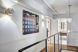 Experience a clean and contemporary space with a vibrant painting and a staircase leading to an upper level.
