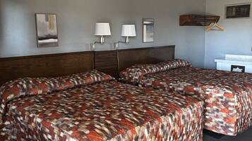 A hotel room with two beds, a wooden headboard, a small desk, and a mirror on the wall.
