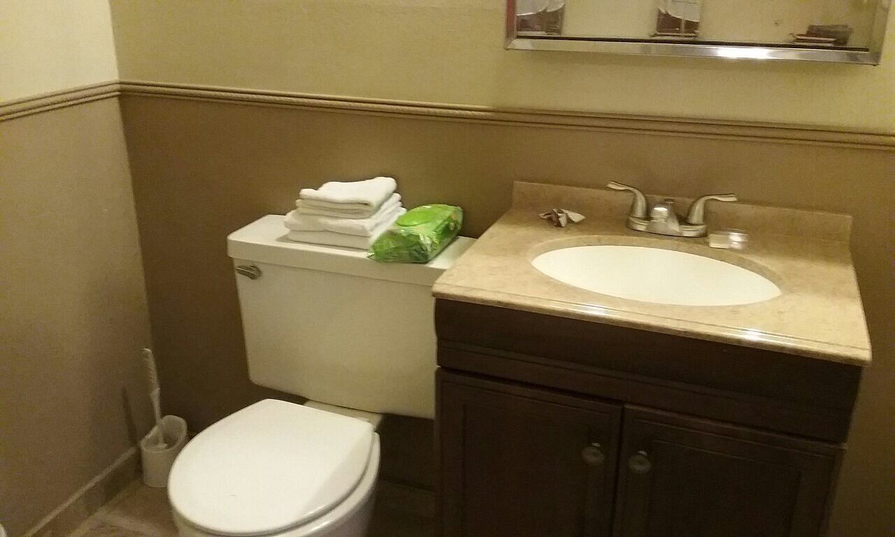 Een kleine badkamer met toilet, wastafel en kastje.