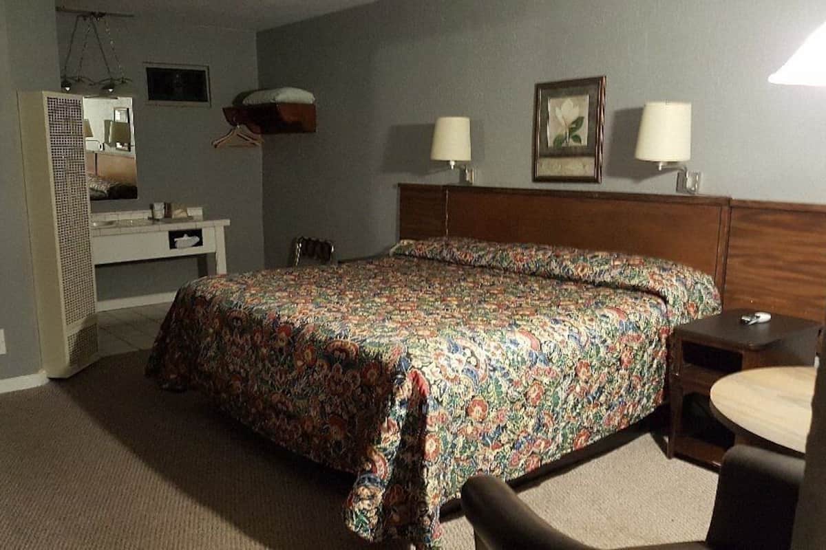 Une chambre d’hôtel comprenant un lit, des tables de chevet, un bureau, une chaise et un miroir.