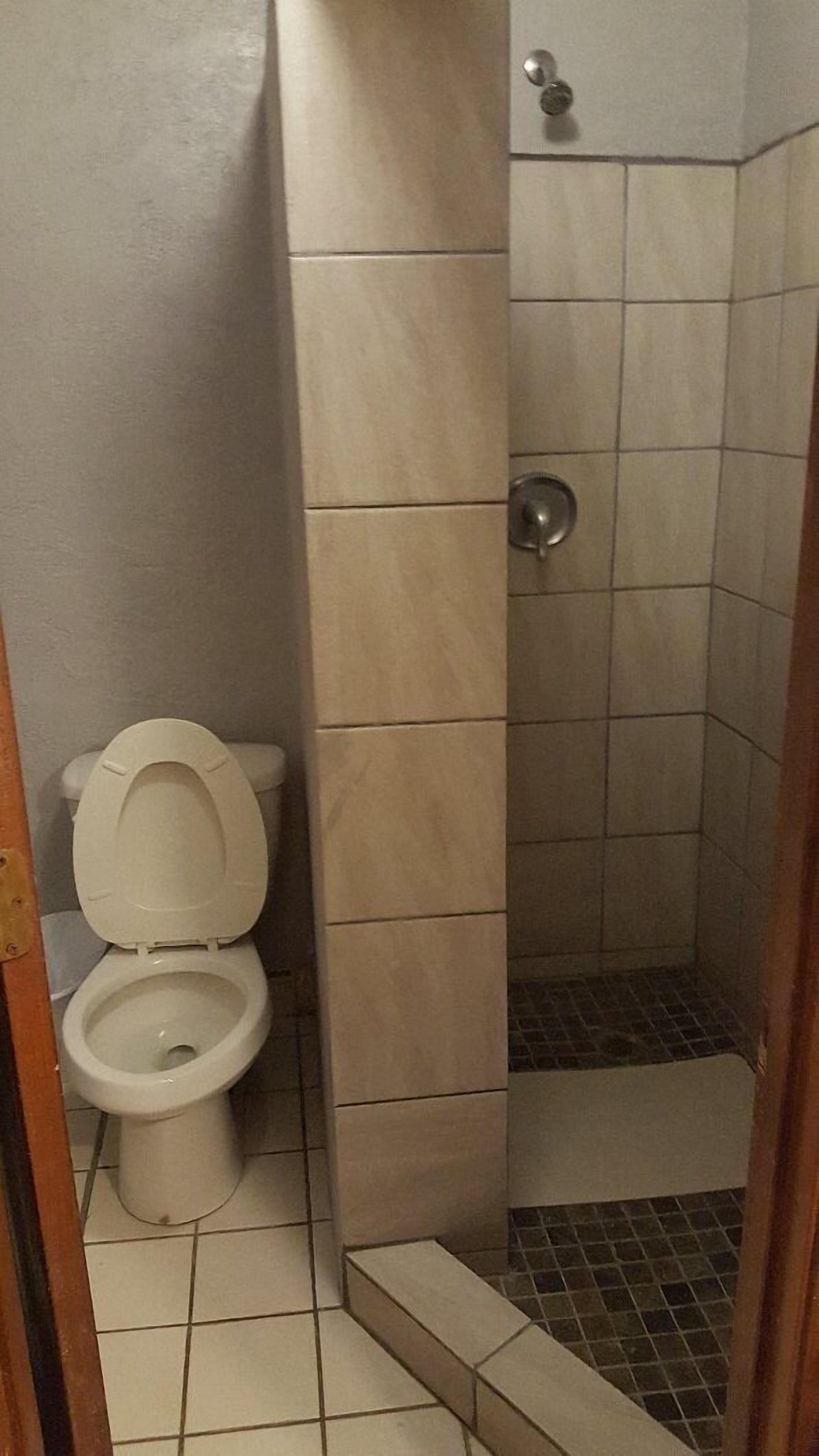 Un baño con inodoro, cabina de ducha y paredes con azulejos.
