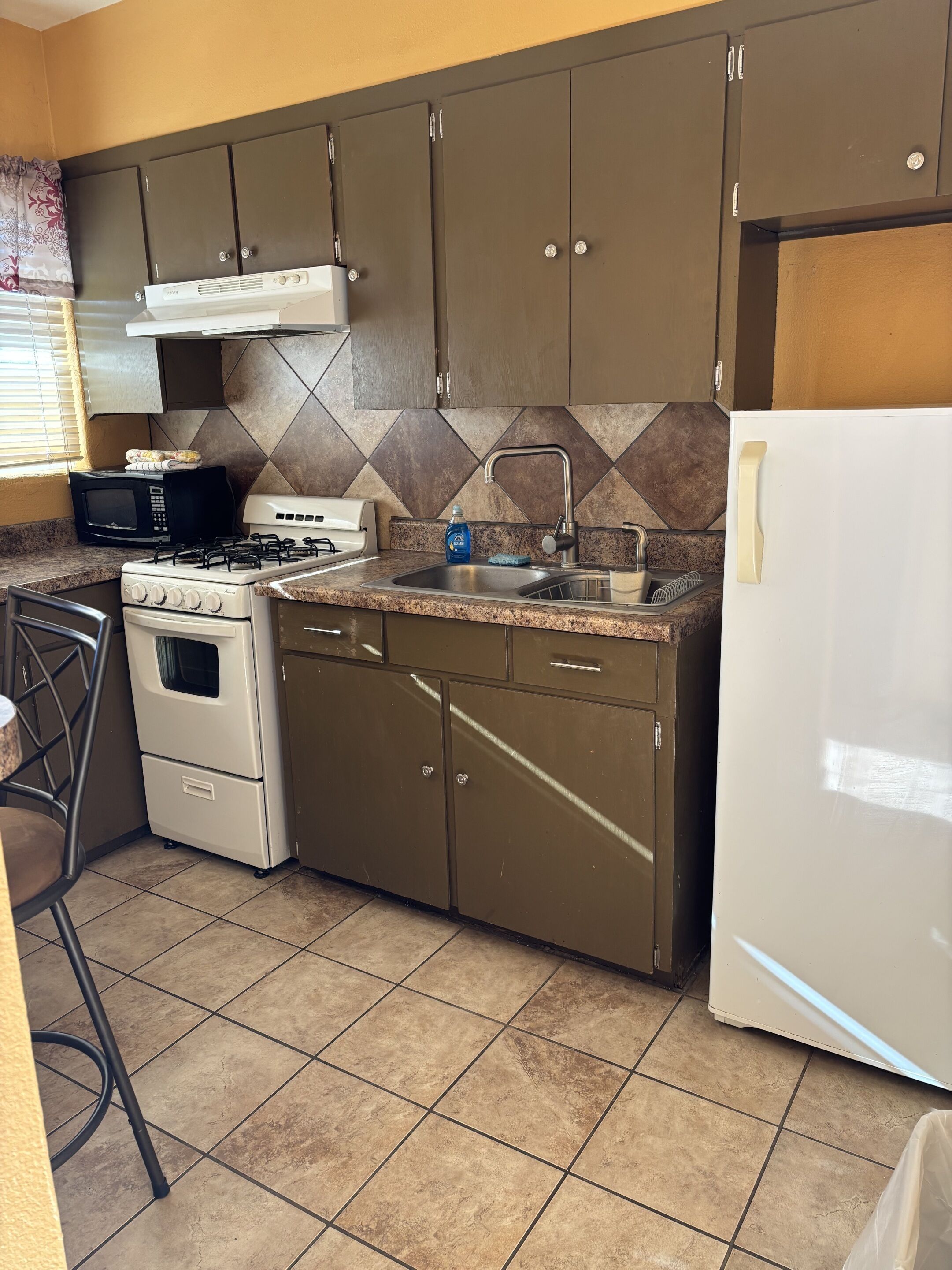 Una cocina equipada con estufa, microondas, fregadero y armarios.