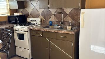 A kitchen with a stove, microwave, sink, and cabinets.