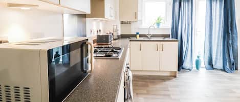 Una cocina moderna con estufa, microondas y lavamanos.