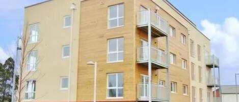 Un edificio de varios pisos con techo plano, ventanas rectangulares y un balcón en el segundo nivel.