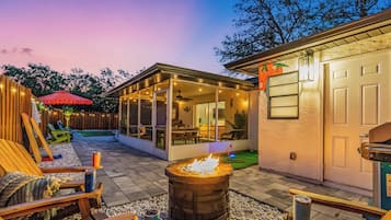 Relax by the fire pit in a comfortable outdoor seating area with a clear view of the interior dining space.