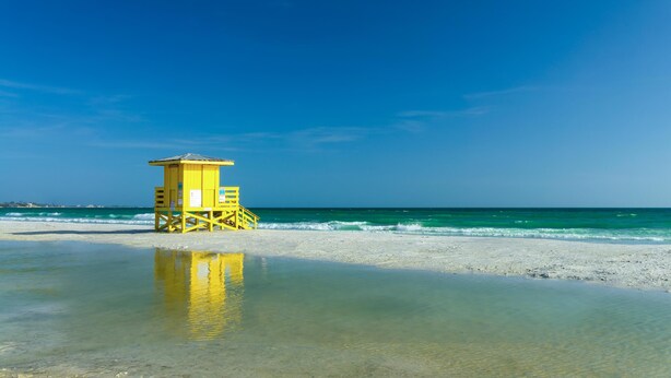 A lifeguard tower on a beach with clear blue sky and calm sea.