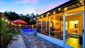 A covered outdoor area with a pool, seating, and a dining area.