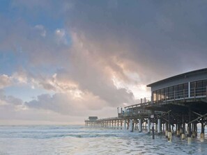 A pier extending into the sea with a building on it.
