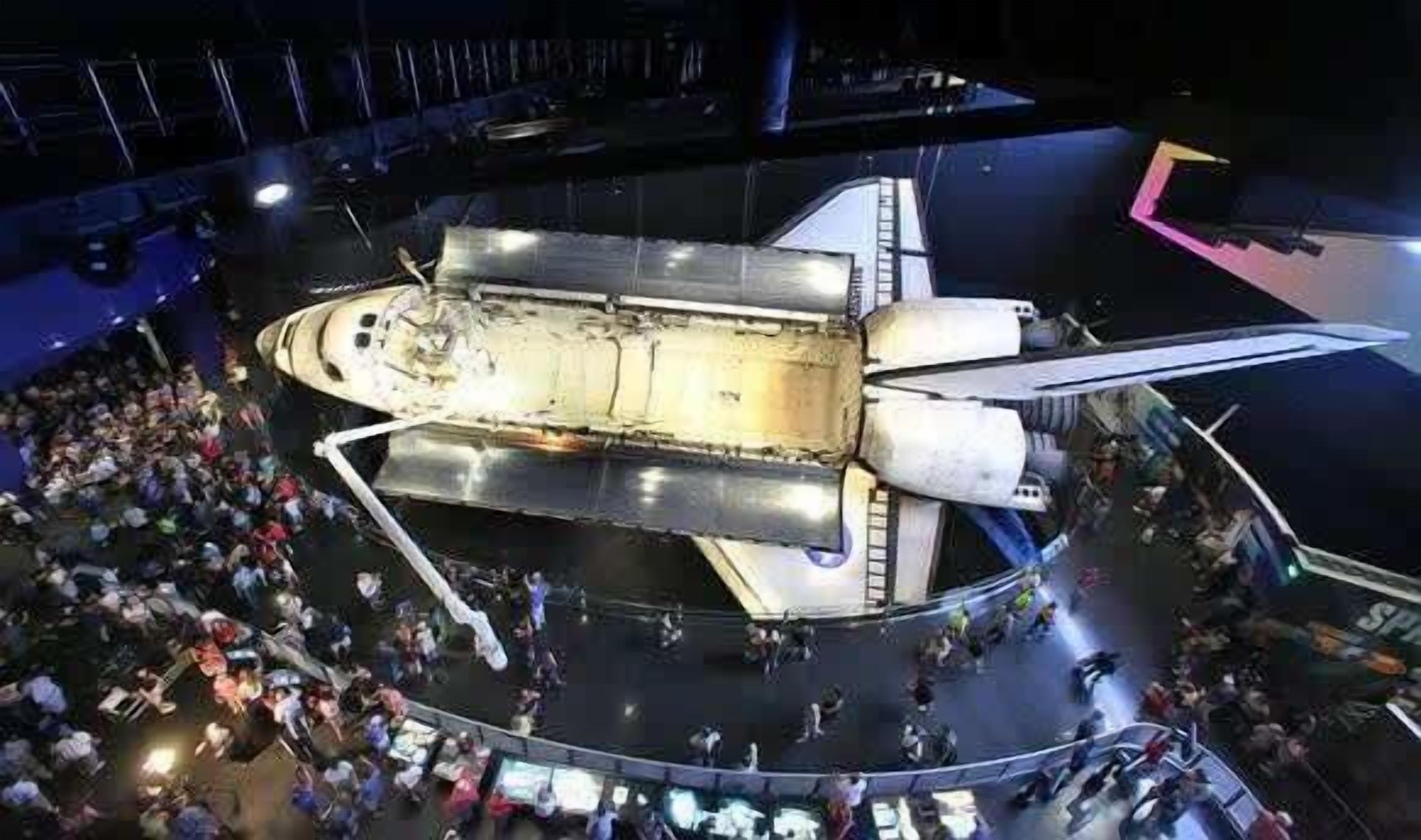 Un transbordador espacial exhibido con una multitud de personas a su alrededor.