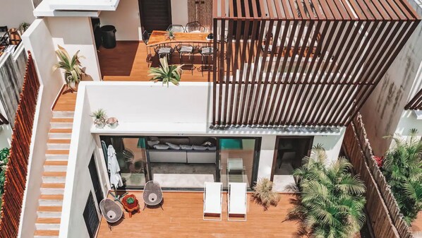Un espacio residencial moderno y de varios niveles, con comedor, asientos y un balcón con plantas.