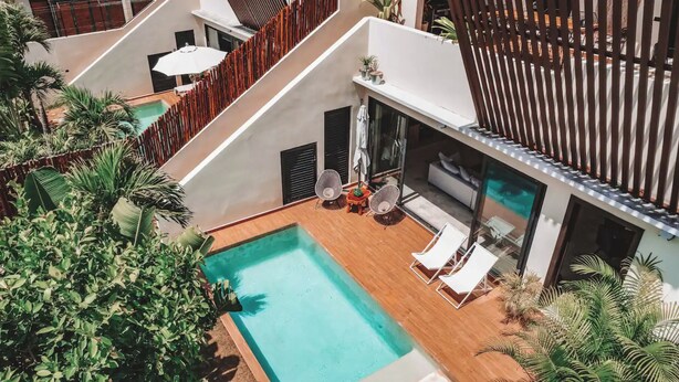 A modern outdoor pool area with lounge chairs, a small table, and potted plants. - Luxury Villa-4BDR Private Pool & Jacuzzi (Tulum)