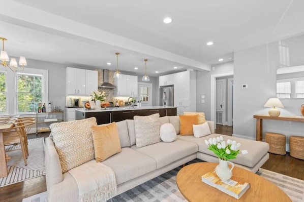 A modern living room with a sofa, coffee table, and a dining area with chairs.