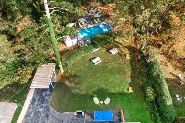 An aerial view of a backyard with a swimming pool, a deck, and a small shed.