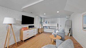 Un salon moderne avec un téléviseur, un canapé et un lit superposé à l’arrière-plan.