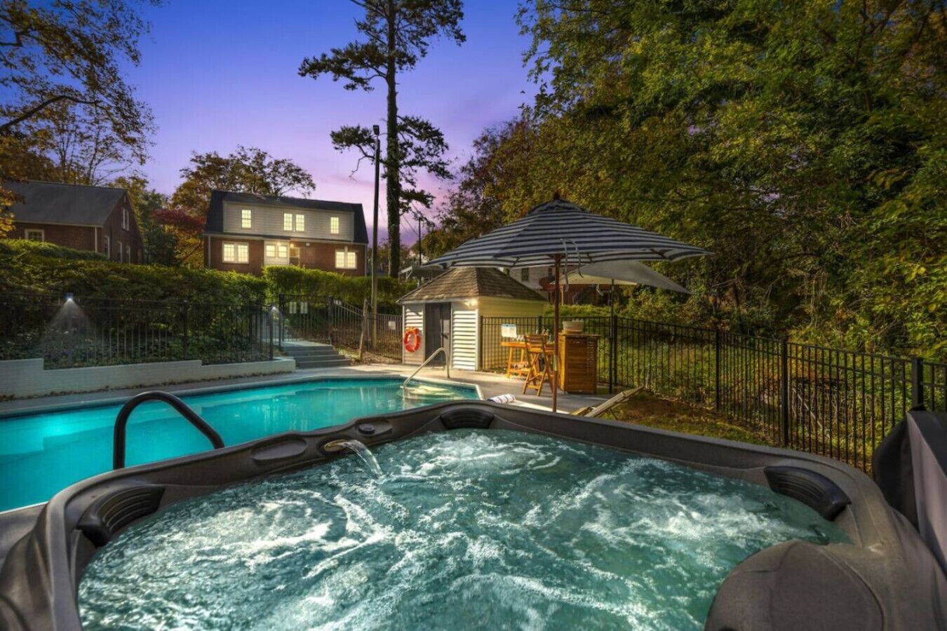 Un jacuzzi con piscina, un porche cubierto y una casa al fondo.