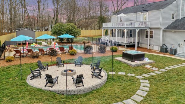 A backyard with a fire pit, outdoor seating, a pool, and a house.