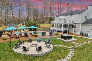 Ein Garten mit Feuerstelle, Sitzgelegenheiten im Freien, einem Pool und einem Haus.
