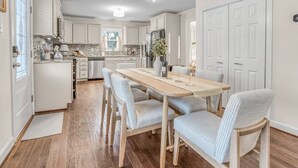 A modern kitchen with white cabinets, a wooden dining table, and striped chairs.