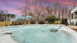 A hot tub with a wooden fence and trees in the background.