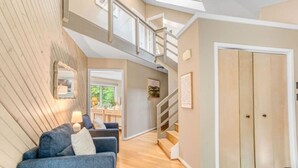 Un intérieur moderne avec un escalier menant à une mezzanine, un ensemble de canapés et une porte.