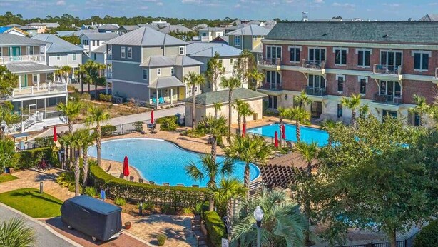 A residential area with a swimming pool surrounded by palm trees and a sign reading "The Village Pool". - One Bedroom, 620 Sq Ft, Seacrest Beach, Free Bikes (Panama City Beach)