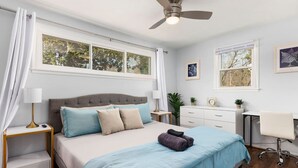 Une chambre à coucher avec un lit, des tables de chevet, un bureau et une chaise.