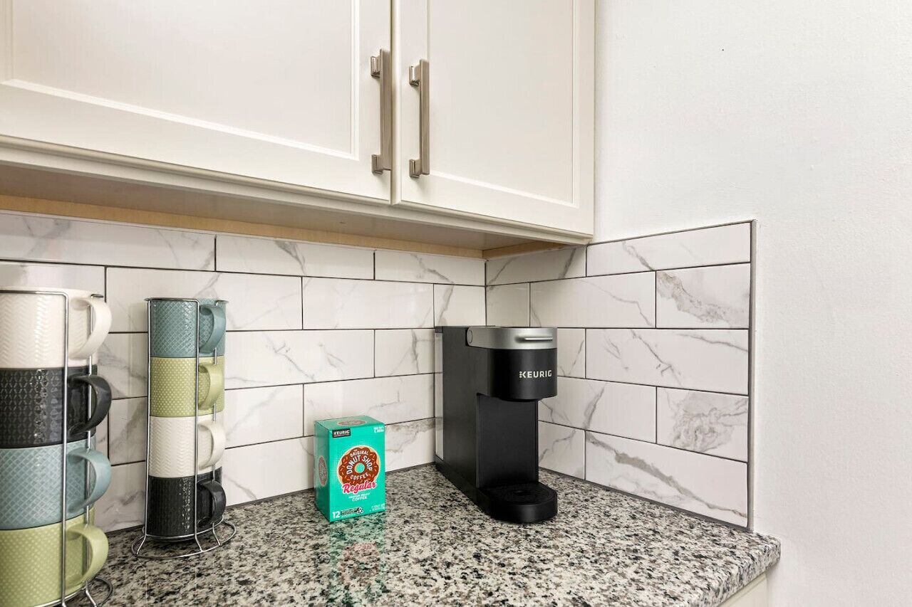 Eine Küche mit weißen Schränken, einer Kaffeemaschine und einem Becherhalter.