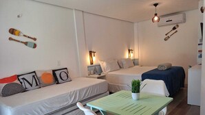 A compact hotel room with two beds, a small table with a plant, and a chair. - Summervilleflatsbg (Cajueiro da Praia)