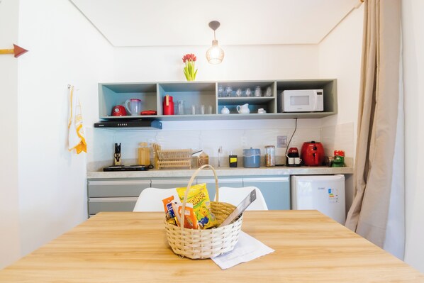 A kitchen with a wooden table, a basket with items, and various kitchen appliances.