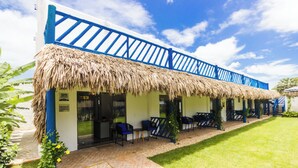 A building with a thatched roof, blue railings, and outdoor seating. - Summervilleflatsbg (Cajueiro da Praia)