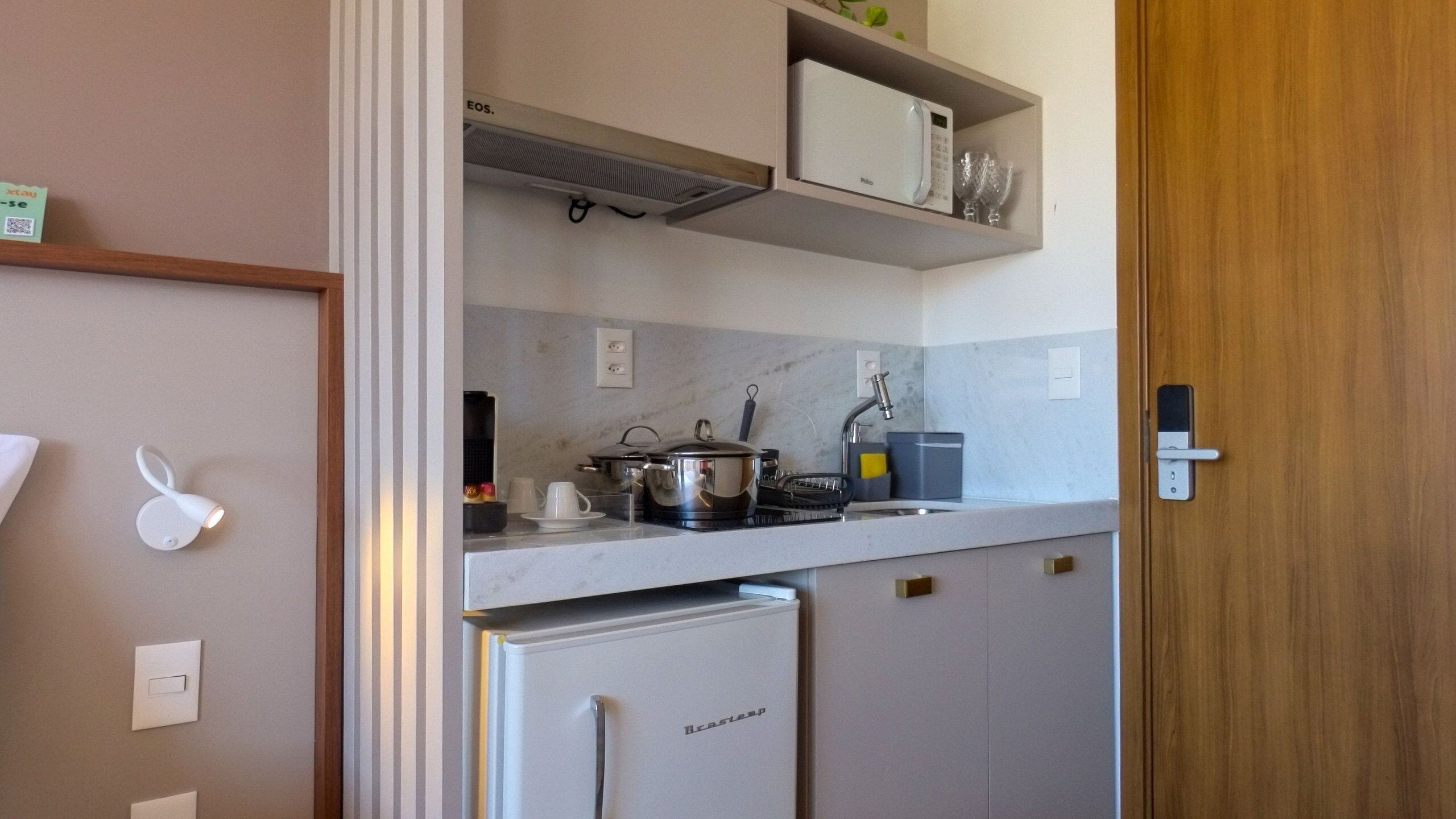 A compact kitchenette with a refrigerator, microwave, and a small sink.