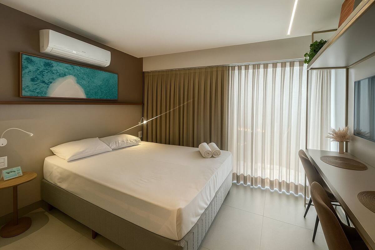 Une chambre d’hôtel comprenant un lit, une table de chevet, une lampe et un bureau avec une chaise.