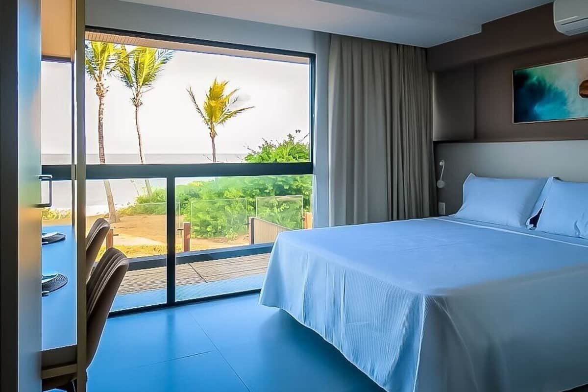 Une chambre d’hôtel avec un grand lit, une vue sur les palmiers et un balcon.
