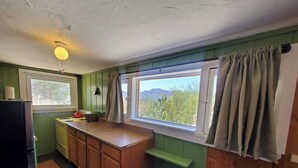 A kitchen with a window, a stove, and a refrigerator.