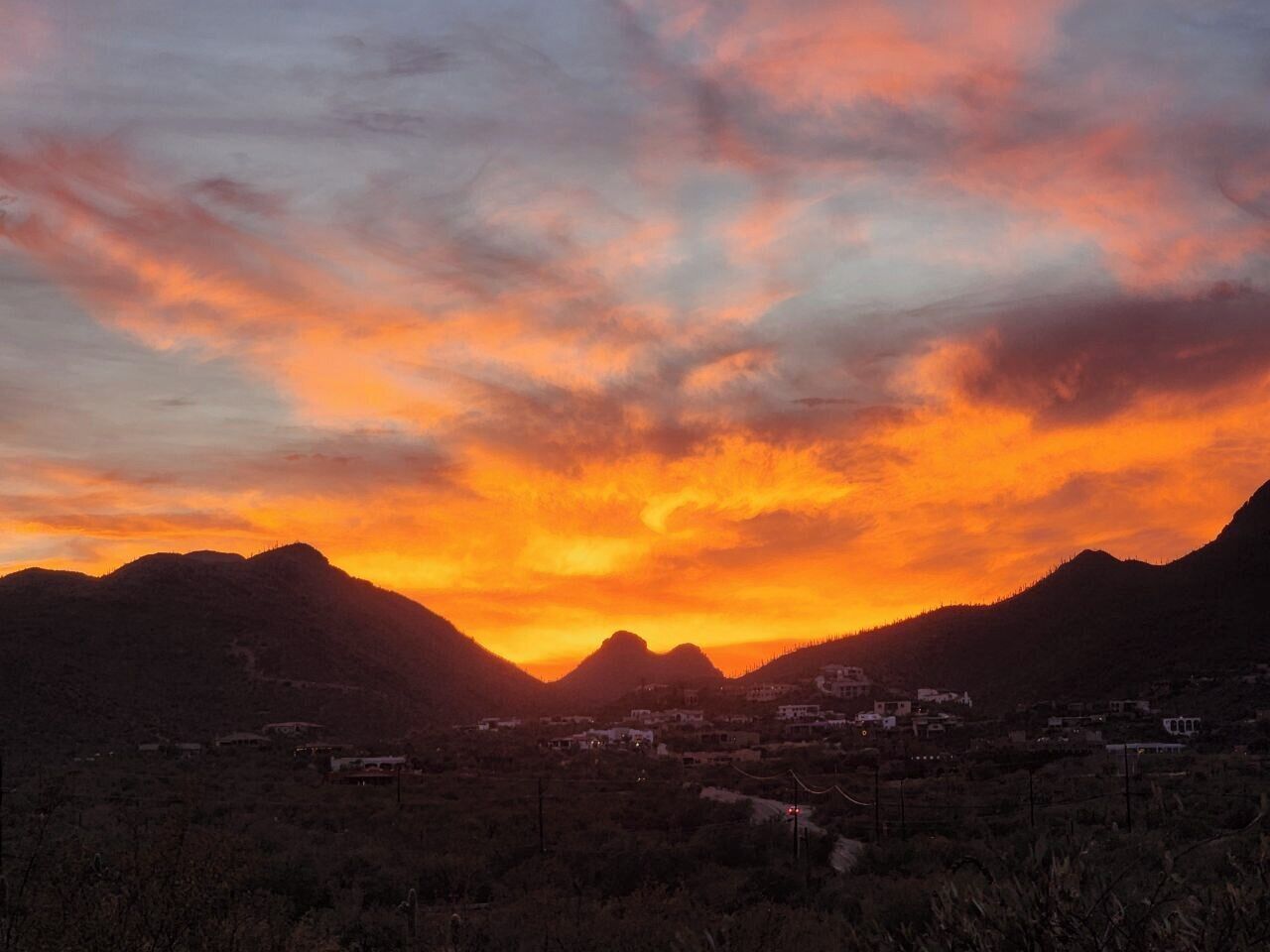 A sunset over a mountainous landscape with a small town in the valley.