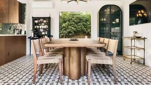 A dining area with a large wooden table surrounded by chairs, a chandelier, and a patterned floor. - Villa Encanto- Luxe 6BRs • Courtyard • Game Room (Long Beach)