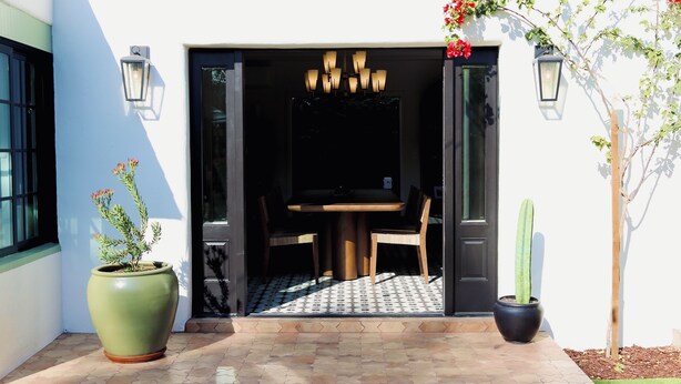 A patio area with a dining table and chairs, a potted plant, and a cactus. - Villa Encanto- Luxe 6BRs • Courtyard • Game Room (Long Beach)