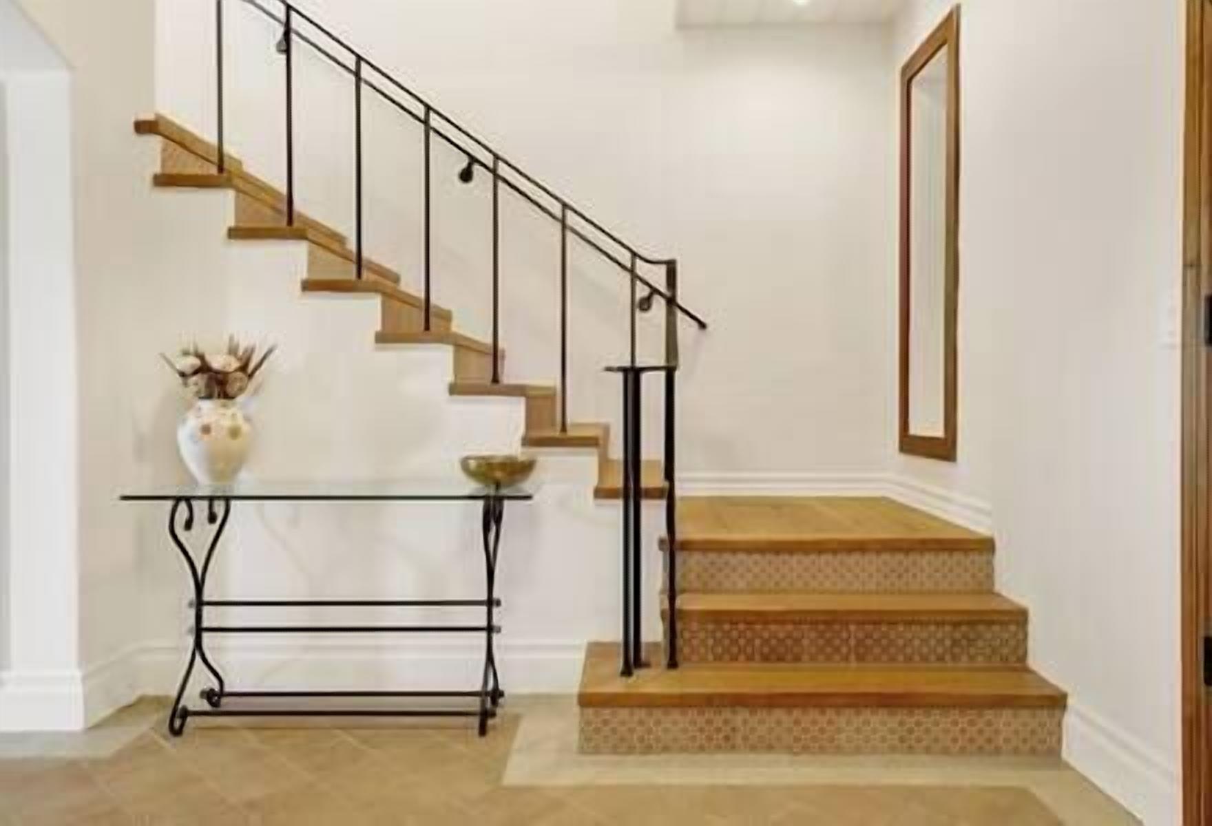 A staircase with a glass console table and a vase.