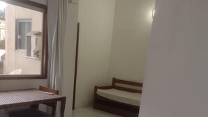 Una habitación de hotel con una cama, una mesita, una silla y un ventanal.