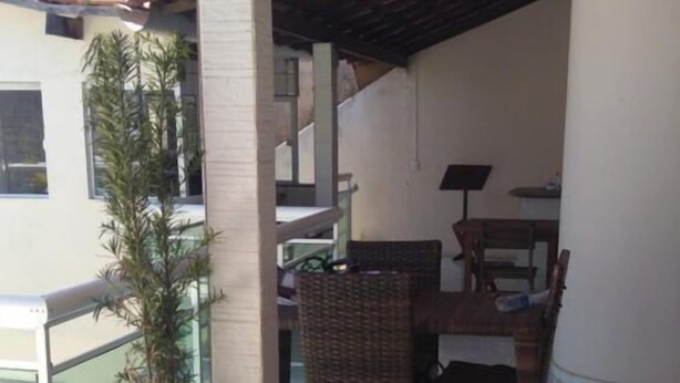 Un balcón con planta en maceta, mobiliario de mimbre y piso de baldosas.