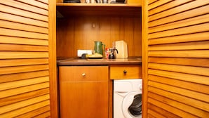Une cuisine compacte dotée de meubles en bois, d’une machine à café, d’une bouilloire et d’un lave-linge.