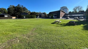 A grassy outdoor area with picnic tables and a building with a dome roof. - Hostel Oslofjord (Bærum)