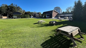 A grassy outdoor area with picnic tables and a swing set. - Hostel Oslofjord (Bærum)